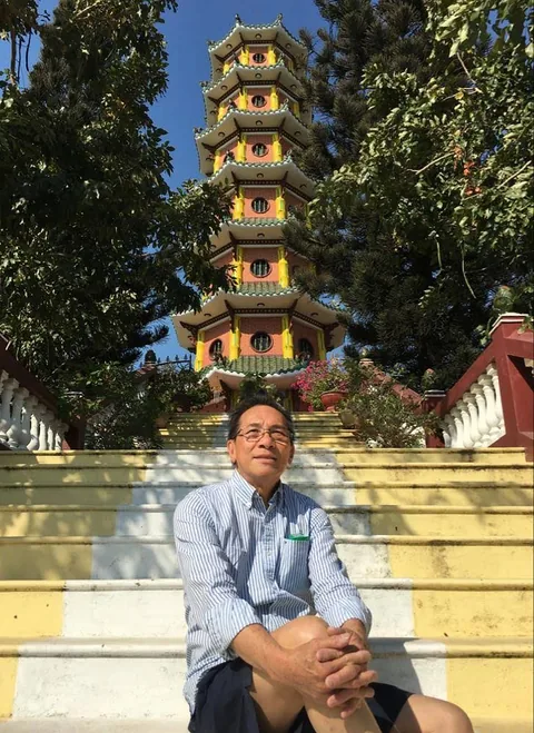 Tommy seated on the steps before a temple pagoda.